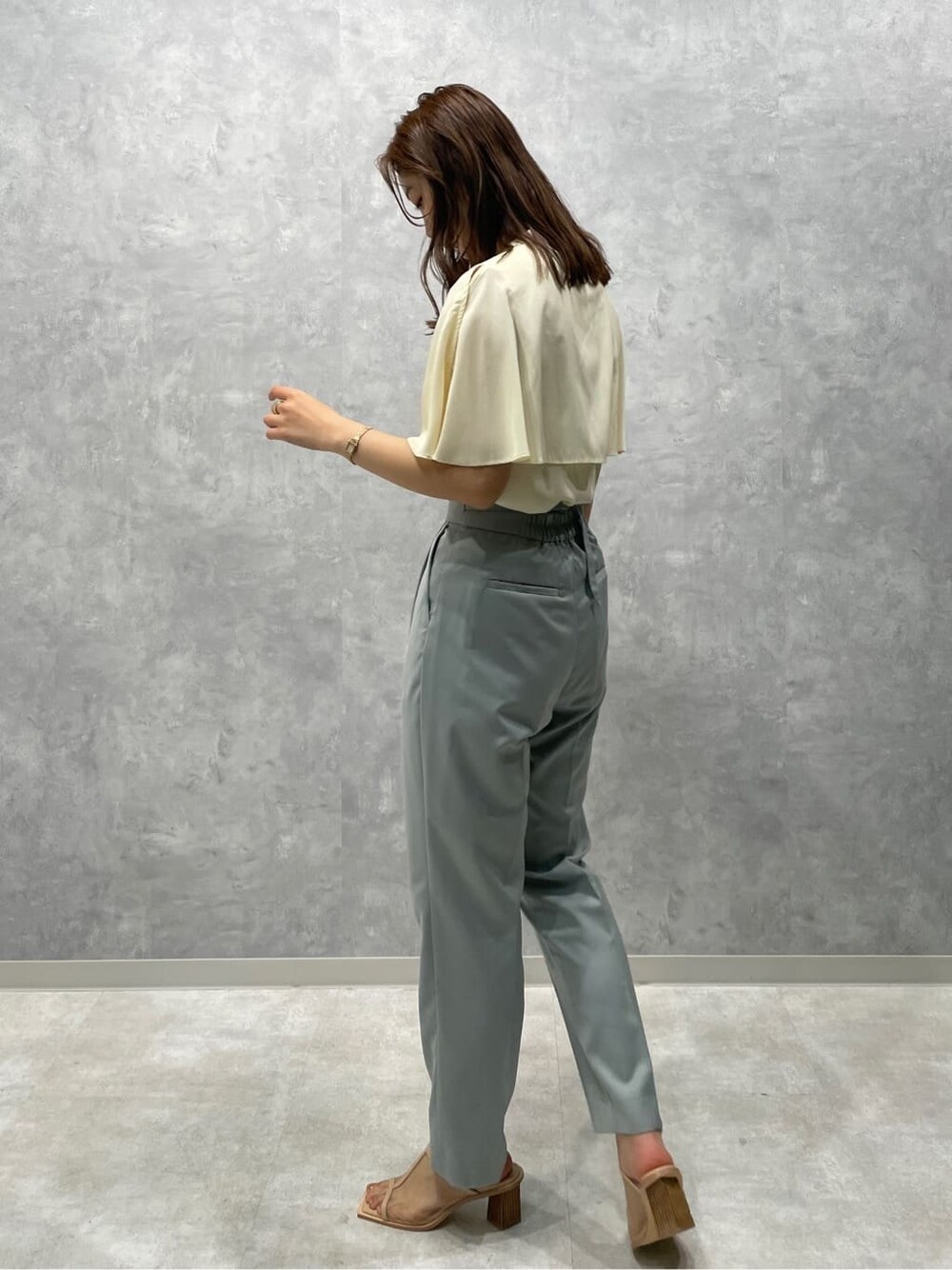 ブルー系のスラックス、ベージュ系のサンダル、ホワイト系のシャツ/ブラウスを着用したレディースの夏コーディネートの2枚目の写真