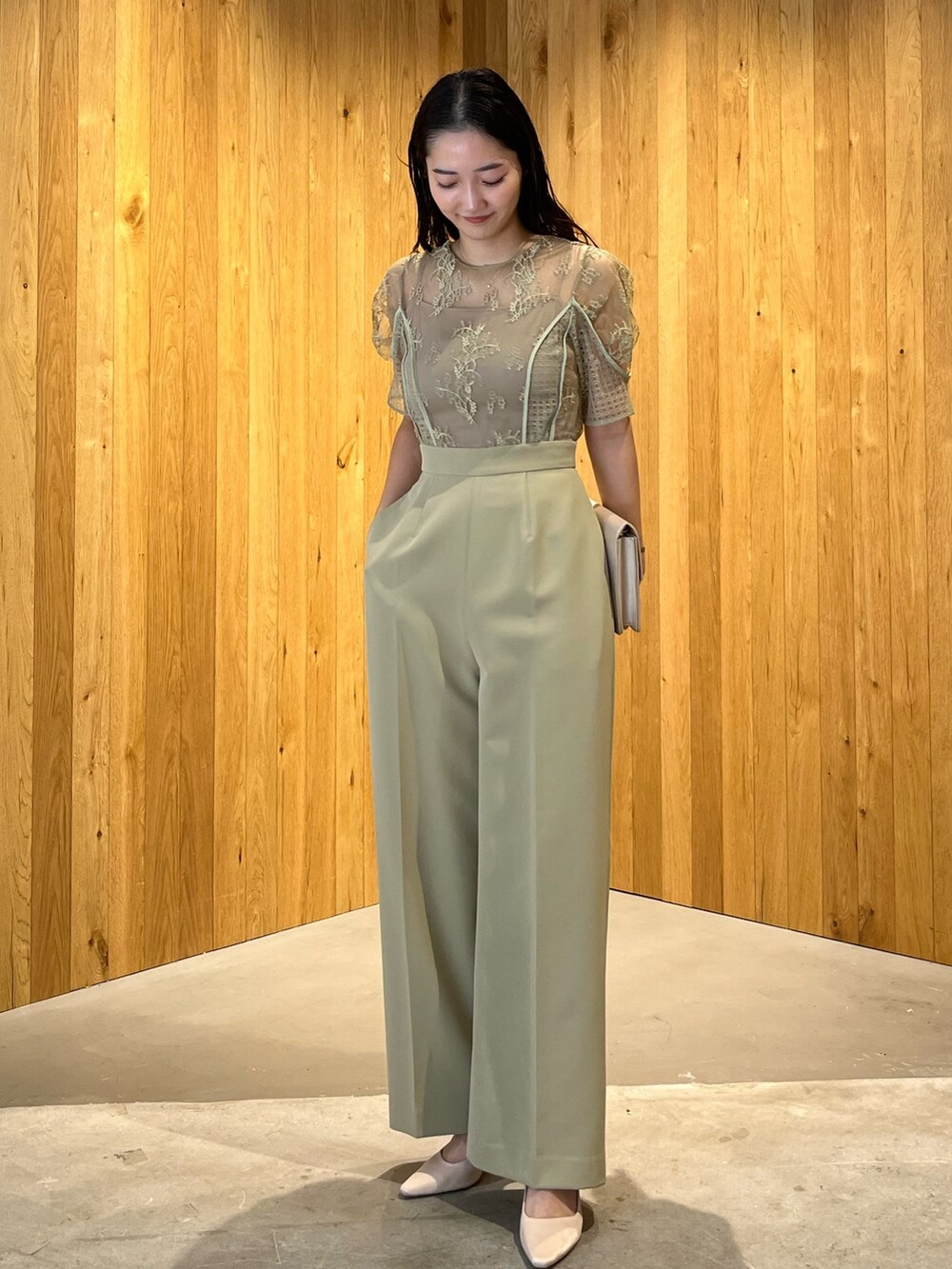 ベージュ系のパンプス、ベージュ系のクラッチバッグ、グリーン系のパンツドレスを着用したレディースの冬コーディネートの2枚目の写真