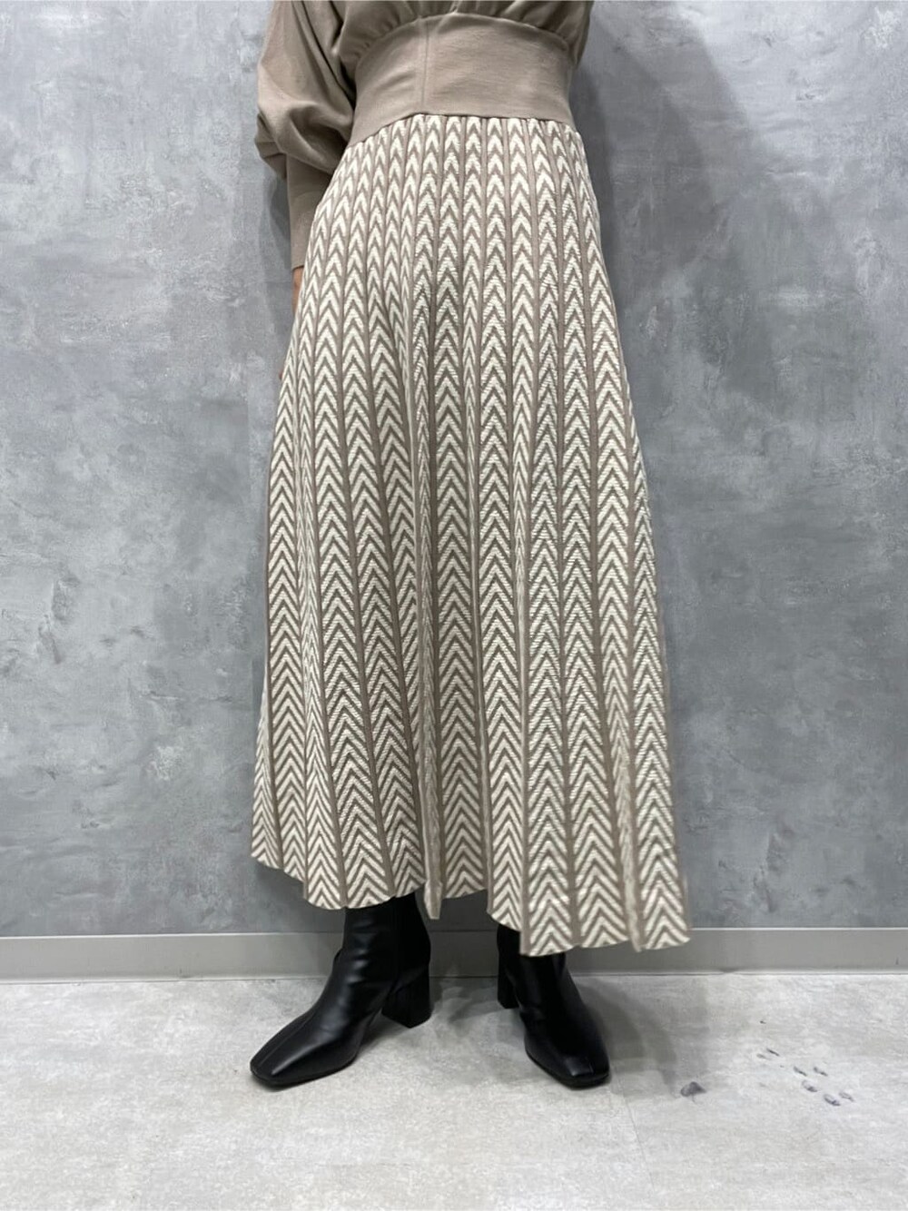 ホワイト系のノーカラーコート、ブラック系のブーツ、ベージュ系のワンピースを着用したレディースの秋コーディネートの8枚目の写真