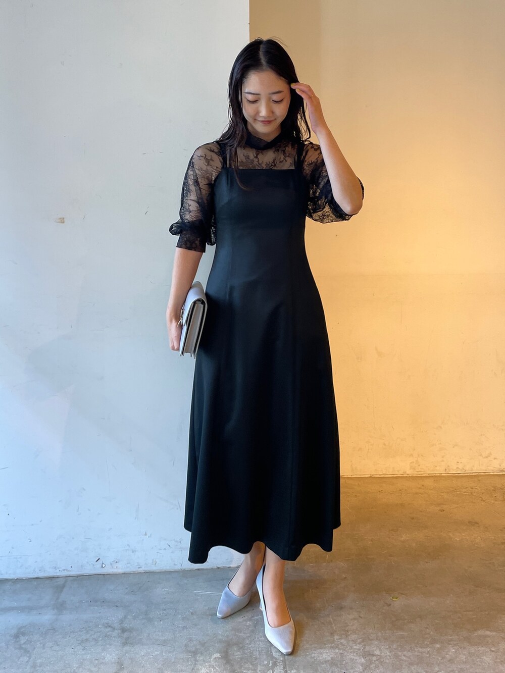 グレー系のパンプス、ブラック系のドレス、グレー系のクラッチバッグを着用したレディースの冬コーディネートの7枚目の写真