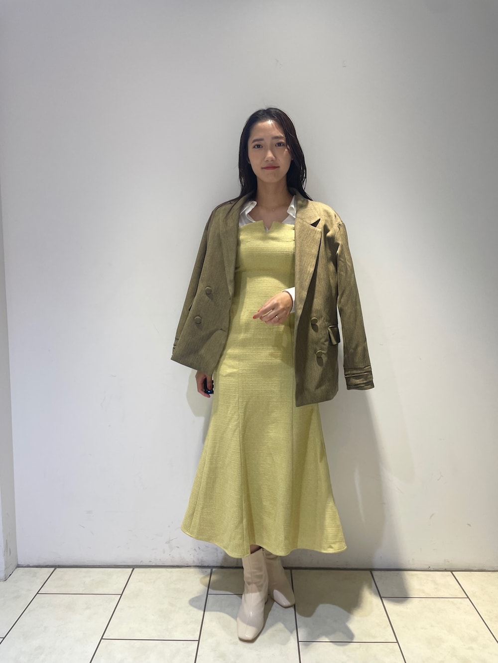 イエロー系のワンピース、ホワイト系のブーツ、ブラウン系のテーラードジャケットを着用したレディースの秋コーディネートの3枚目の写真