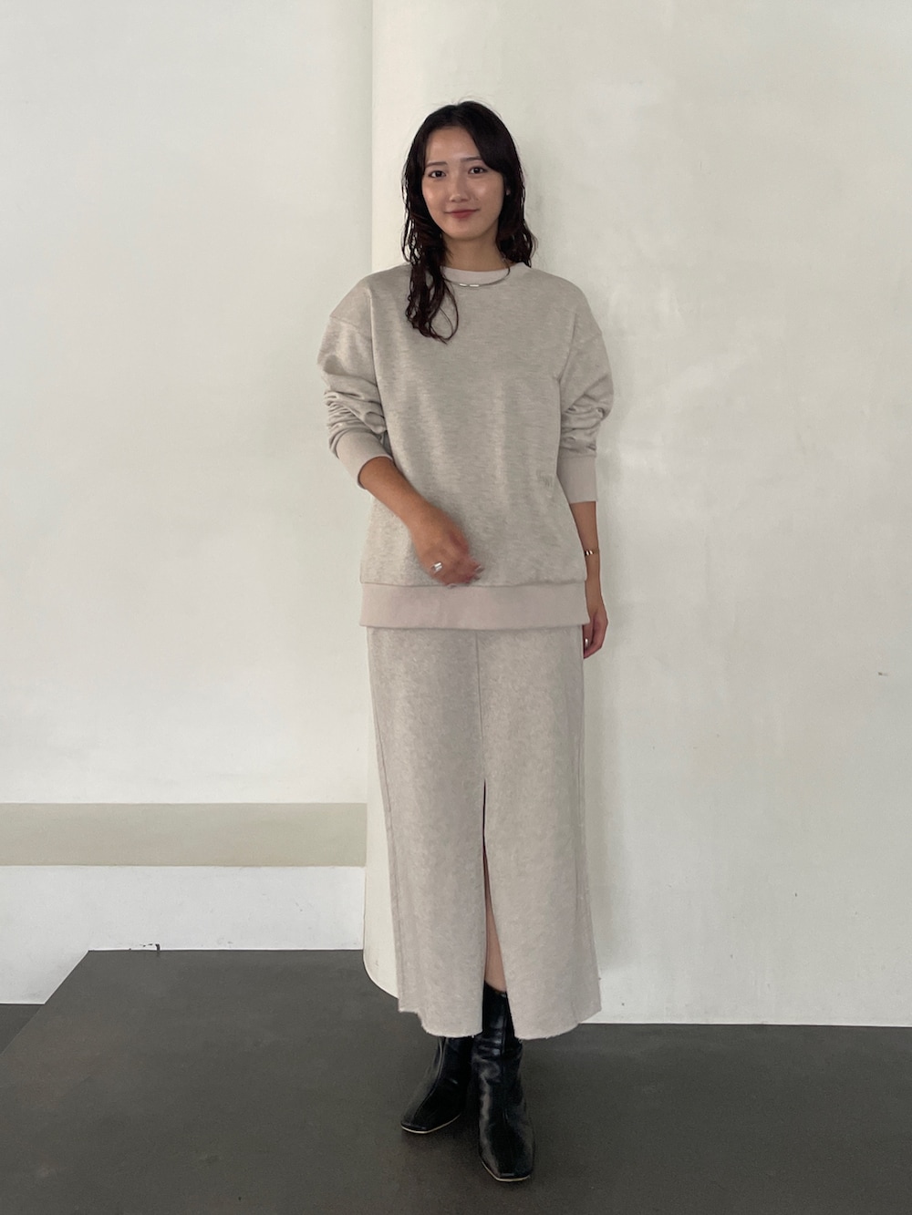 ブラック系のブーツ、ベージュ系のスカート、ベージュ系のスウェットを着用したレディースの秋コーディネートの2枚目の写真