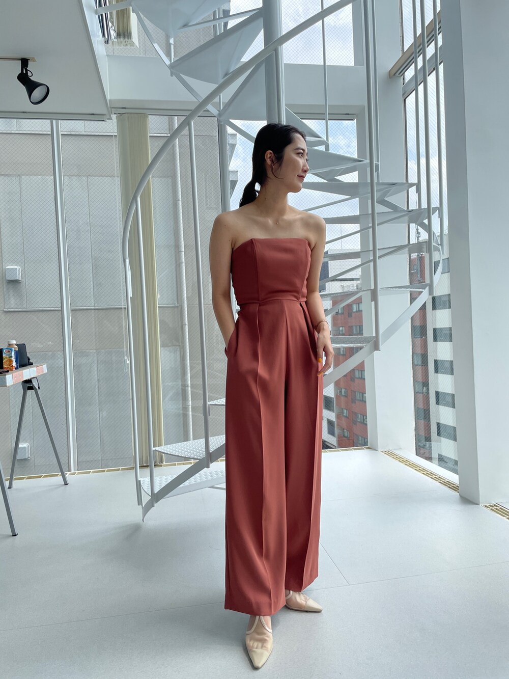 ベージュ系のパンプス、オレンジ系のパンツドレス、ベージュ系のテーラードジャケットを着用したレディースの夏コーディネートの6枚目の写真