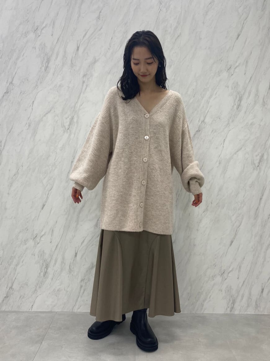 ブラック系のブーツ、ベージュ系のスカート、ホワイト系のカーディガン/ボレロを着用したレディースの秋コーディネートの3枚目の写真
