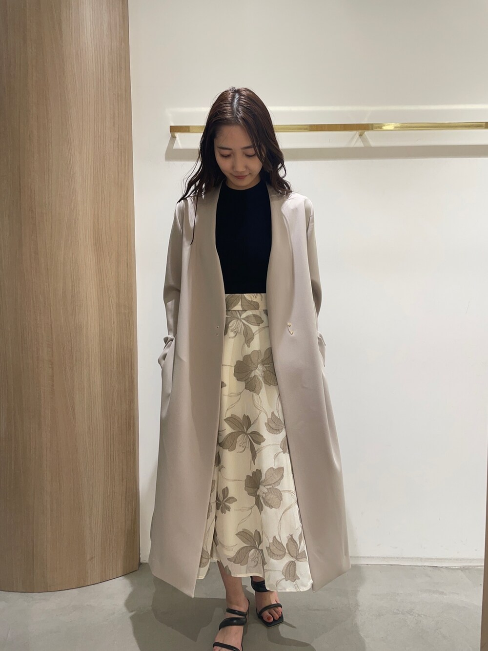 ブラック系のニット/セーター、ブラック系のサンダル、ベージュ系のスカートを着用したレディースの春コーディネートの2枚目の写真