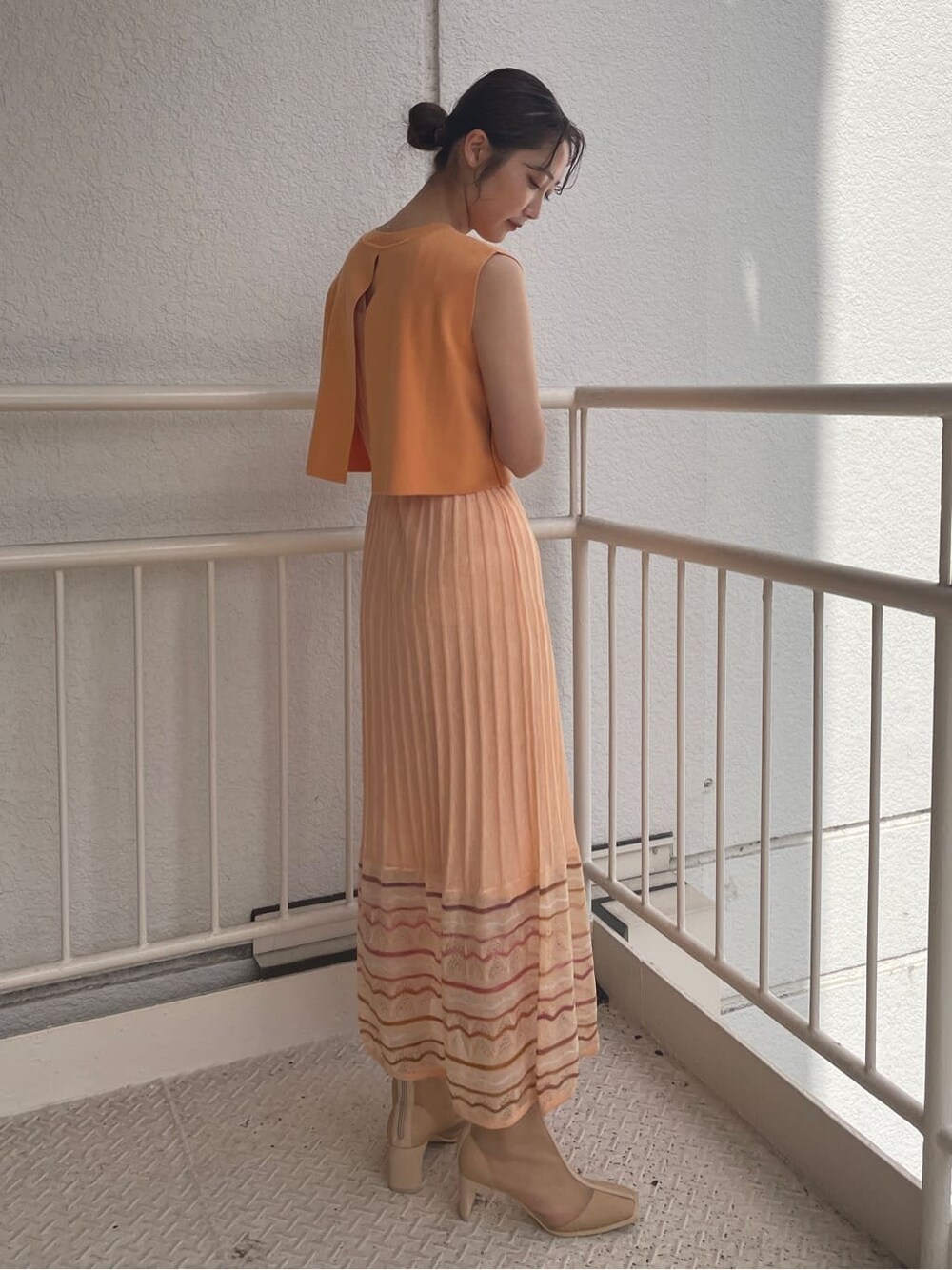 ベージュ系のブーツ、ベージュ系のテーラードジャケット、オレンジ系のワンピースを着用したレディースの春コーディネートの6枚目の写真