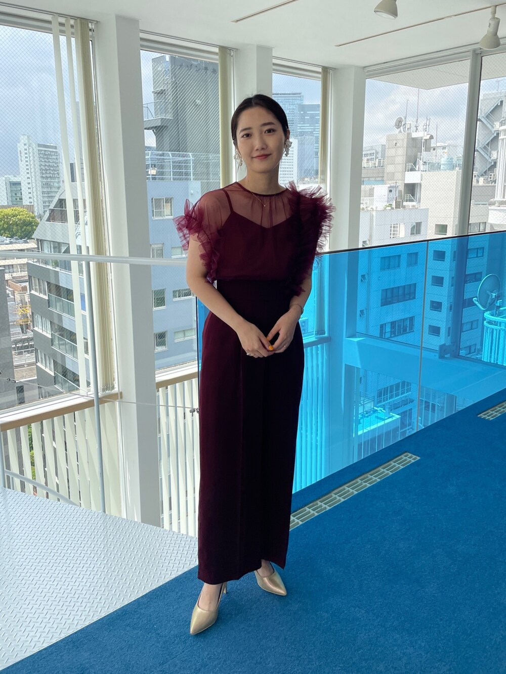 ゴールド系のパンプス、レッド系のパンツドレスを着用したレディースの春コーディネートの3枚目の写真
