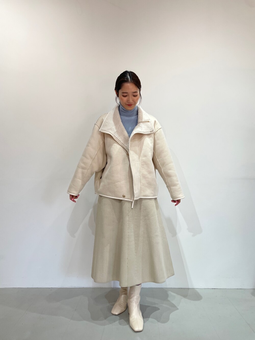 ブルー系のニット/セーター、ホワイト系のジャンパースカート、ホワイト系のブーツを着用したレディースの夏コーディネートの2枚目の写真