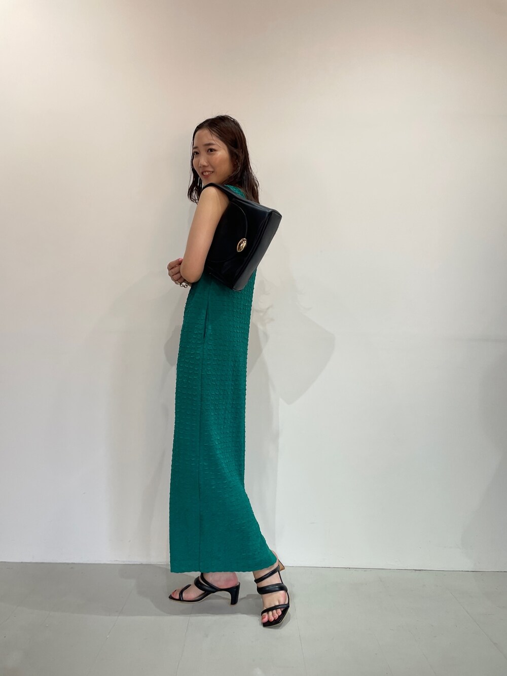 グリーン系のワンピース、ブラック系のサンダル、ブラック系のハンドバッグを着用したレディースの夏コーディネートの5枚目の写真