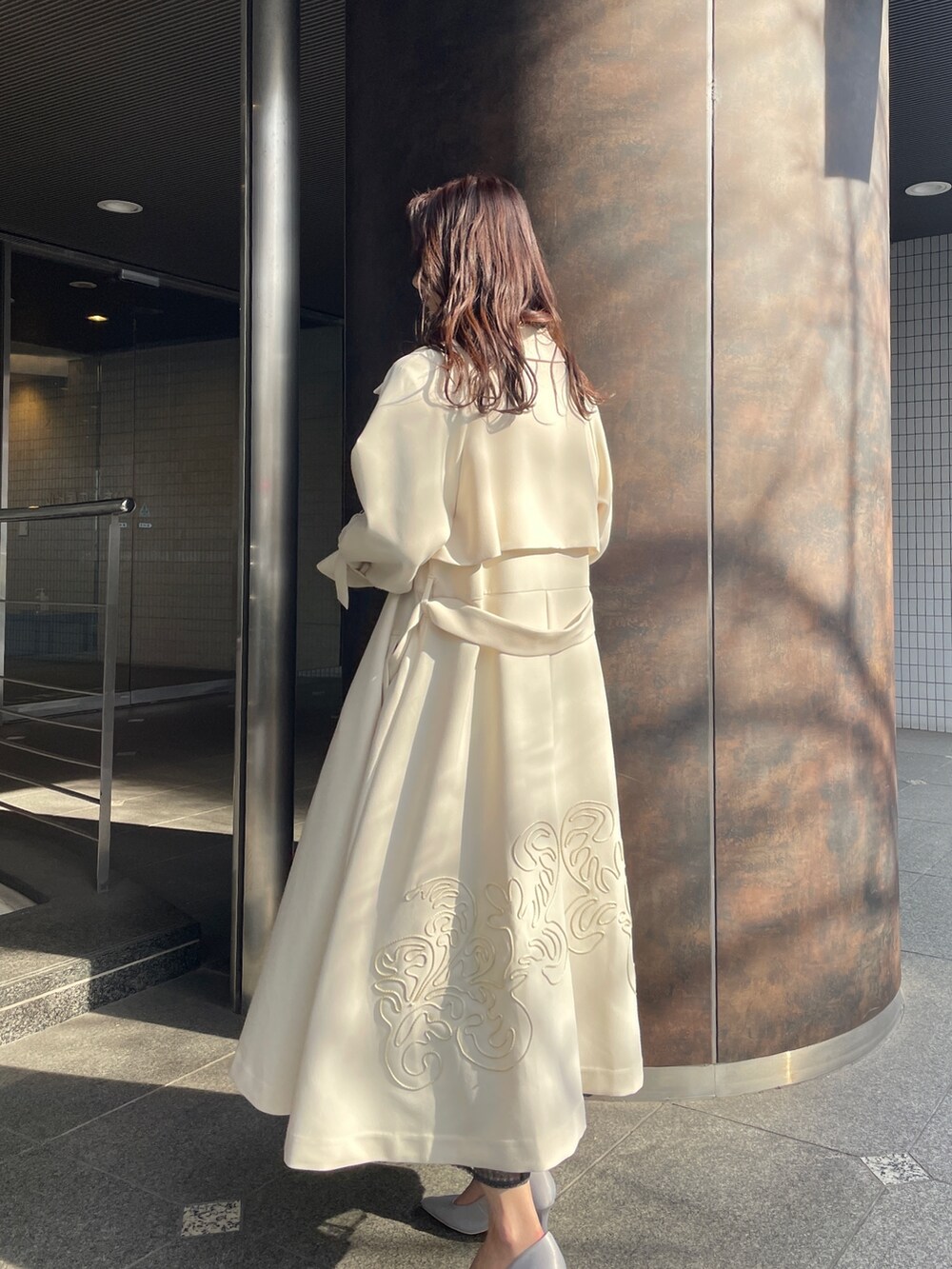 グレー系のドレス、グレー系のパンプス、ホワイト系のトレンチコートを着用したレディースの冬コーディネートの2枚目の写真