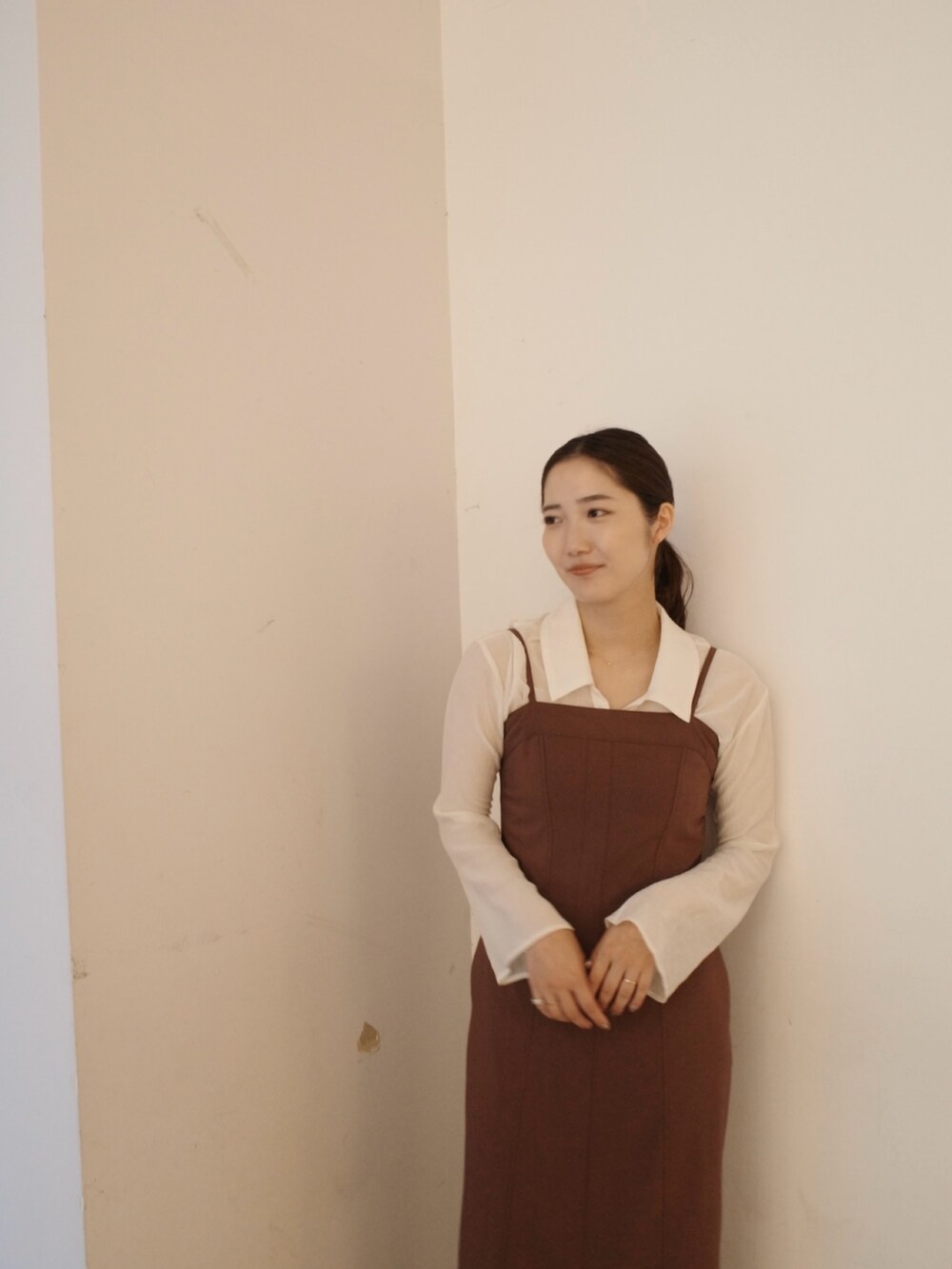 グレー系のステンカラーコート、ブラウン系のワンピースを着用したレディースの秋コーディネートの10枚目の写真