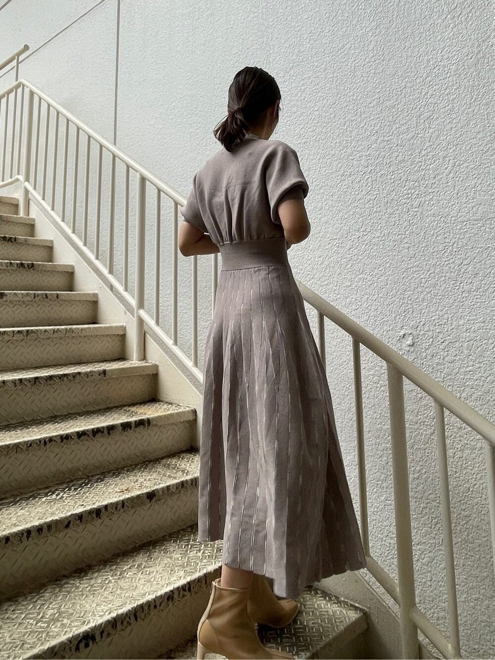 ベージュ系のトレンチコート、グレー系のワンピース、ベージュ系のブーツを着用したレディースの春コーディネートの8枚目の写真