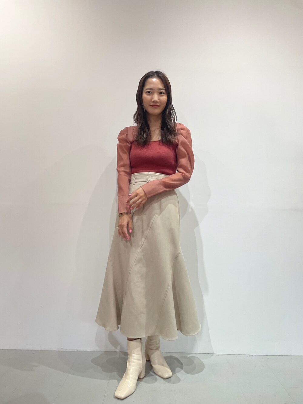 ホワイト系のブーツ、ピンク系のニット/セーター、ベージュ系のスカートを着用したレディースの秋コーディネートの6枚目の写真