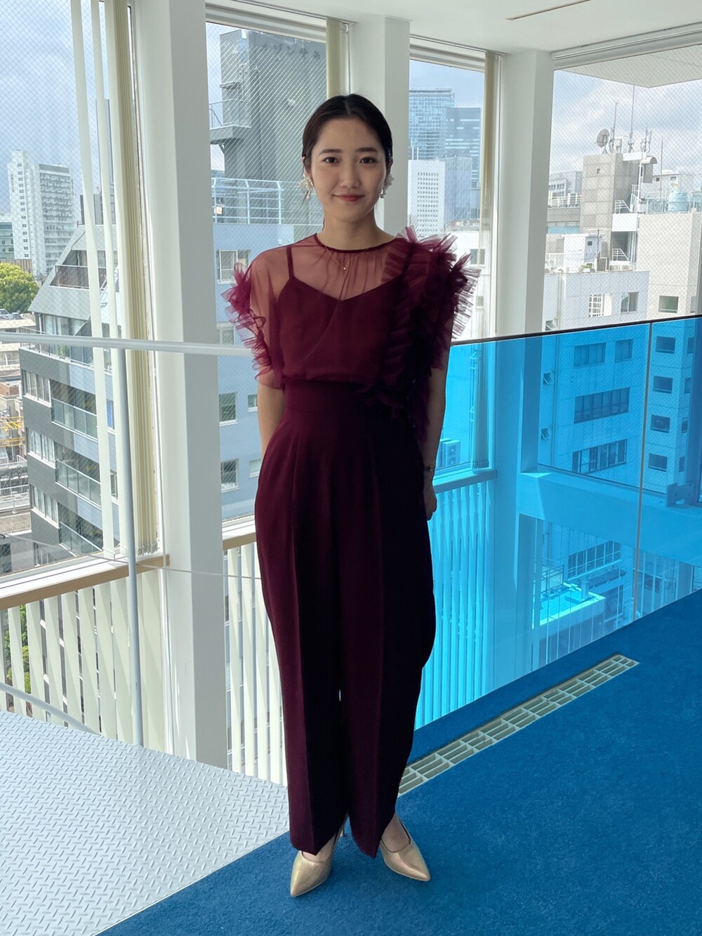 ゴールド系のパンプス、レッド系のパンツドレスを着用したレディースの春コーディネートの2枚目の写真