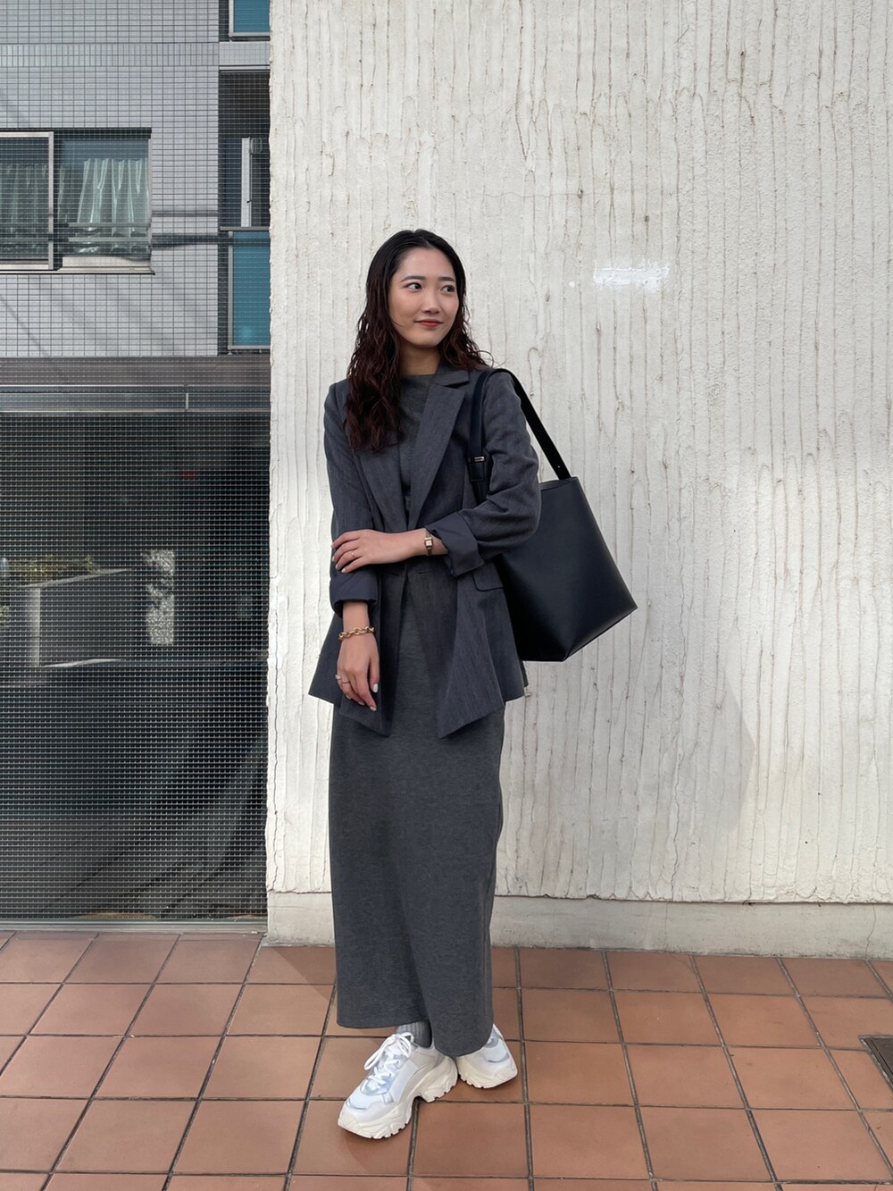 ブラック系のショルダーバッグ、グレー系のワンピース、ホワイト系のスニーカーを着用したレディースの冬コーディネートの9枚目の写真