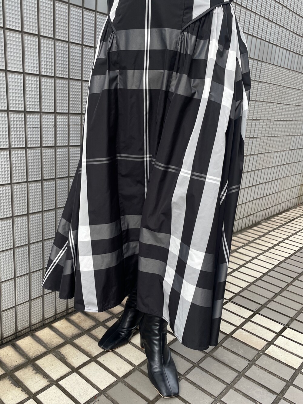 ブラック系のワンピース、ブラック系のブーツ、ブラック系のハンドバッグを着用したレディースの冬コーディネートの9枚目の写真