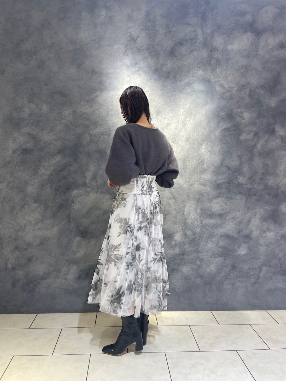 ブラック系のスカート、ブラック系のブーツ、グレー系のニット/セーターを着用したレディースの秋コーディネートの4枚目の写真