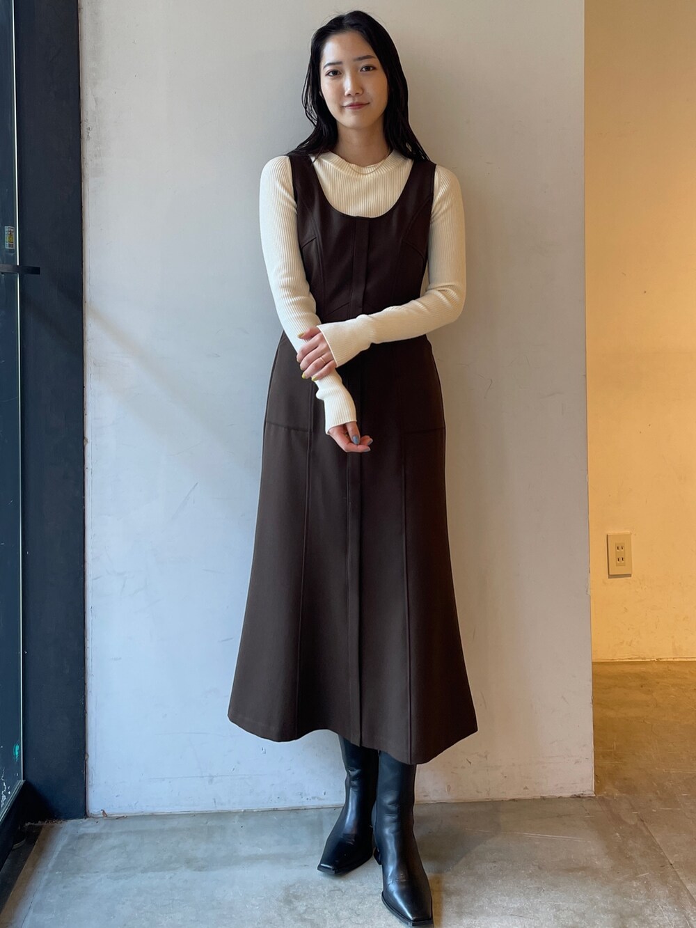 ブラック系のブーツ、ホワイト系のニット/セーター、ブラウン系のジャンパースカートを着用したレディースの冬コーディネートの3枚目の写真