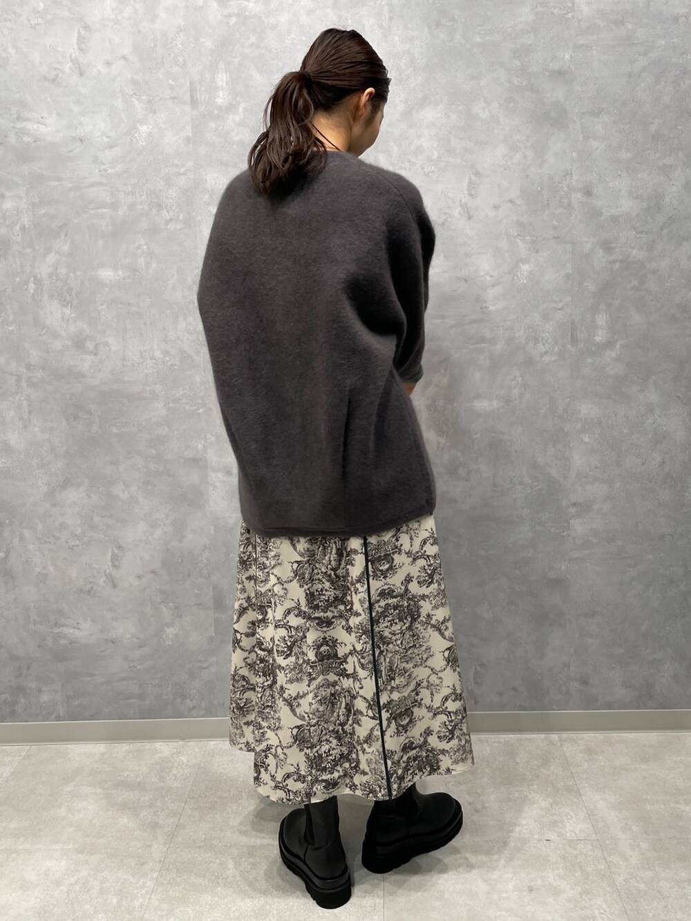 グレー系のカーディガン/ボレロ、ホワイト系のワンピース、ブラック系のブーツを着用したレディースの冬コーディネートの3枚目の写真