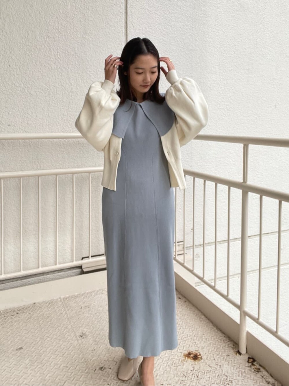 ブルー系のワンピース、ブラック系のハンドバッグ、ホワイト系のパンプスを着用したレディースの冬コーディネートの4枚目の写真