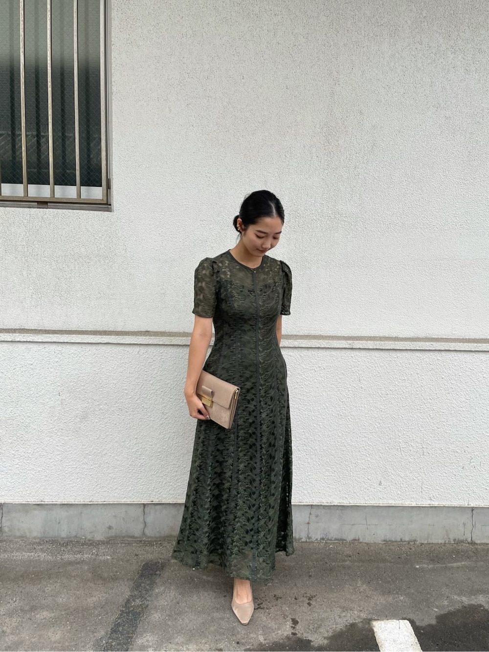 グリーン系のドレス、ベージュ系のパンプス、ブラウン系のクラッチバッグを着用したレディースの夏コーディネートの2枚目の写真