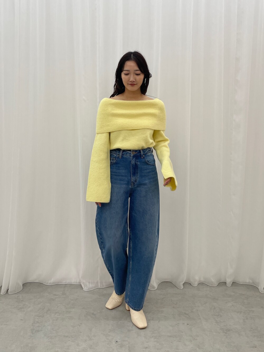 ブルー系のデニムパンツ、ホワイト系のブーツ、イエロー系のニット/セーターを着用したレディースの秋コーディネートの2枚目の写真