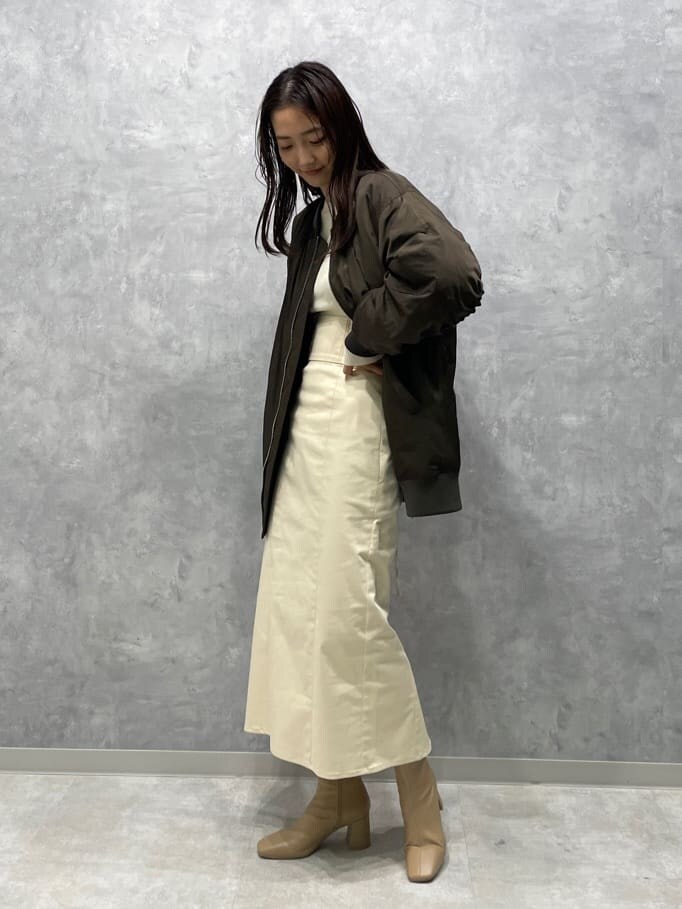 ベージュ系のブーツ、ホワイト系のニット/セーター、ブラウン系のMA-1を着用したレディースの秋コーディネートの2枚目の写真