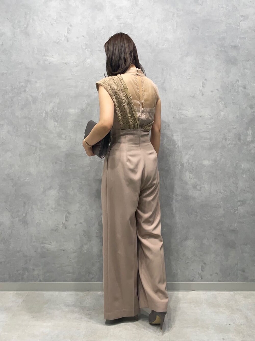 シルバー系のパンプス、シルバー系のクラッチバッグ、ベージュ系のパンツドレスを着用したレディースの夏コーディネートの3枚目の写真