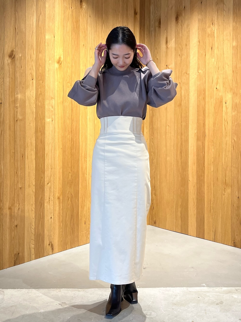 ブラック系のブーツ、ホワイト系のスカート、ベージュ系のニット/セーターを着用したレディースの冬コーディネートの2枚目の写真