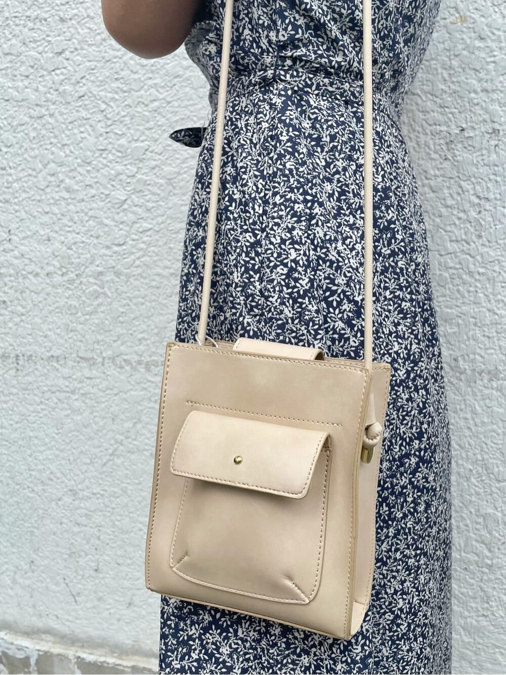 ベージュ系のハンドバッグ、ブルー系のワンピース、ゴールド系のネックレスを着用したレディースの夏コーディネートの6枚目の写真