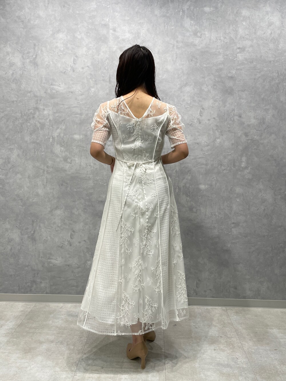 ベージュ系のその他アウター、ゴールド系のパンプス、ホワイト系のドレスを着用したレディースの冬コーディネートの6枚目の写真