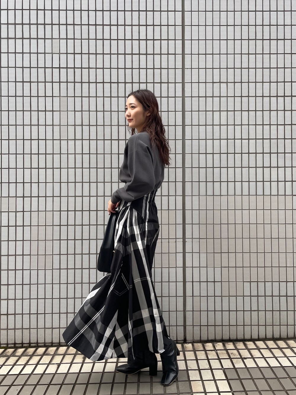 ブラック系のワンピース、ブラック系のブーツ、ブラック系のハンドバッグを着用したレディースの冬コーディネートの5枚目の写真