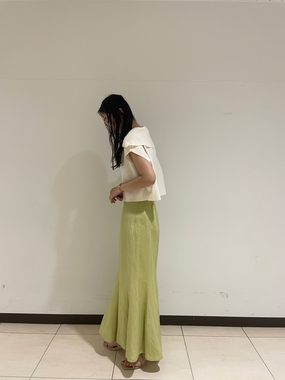 ホワイト系のニット/セーター、ベージュ系のサンダル、グリーン系のスカートを着用したレディースの春コーディネートの5枚目の写真