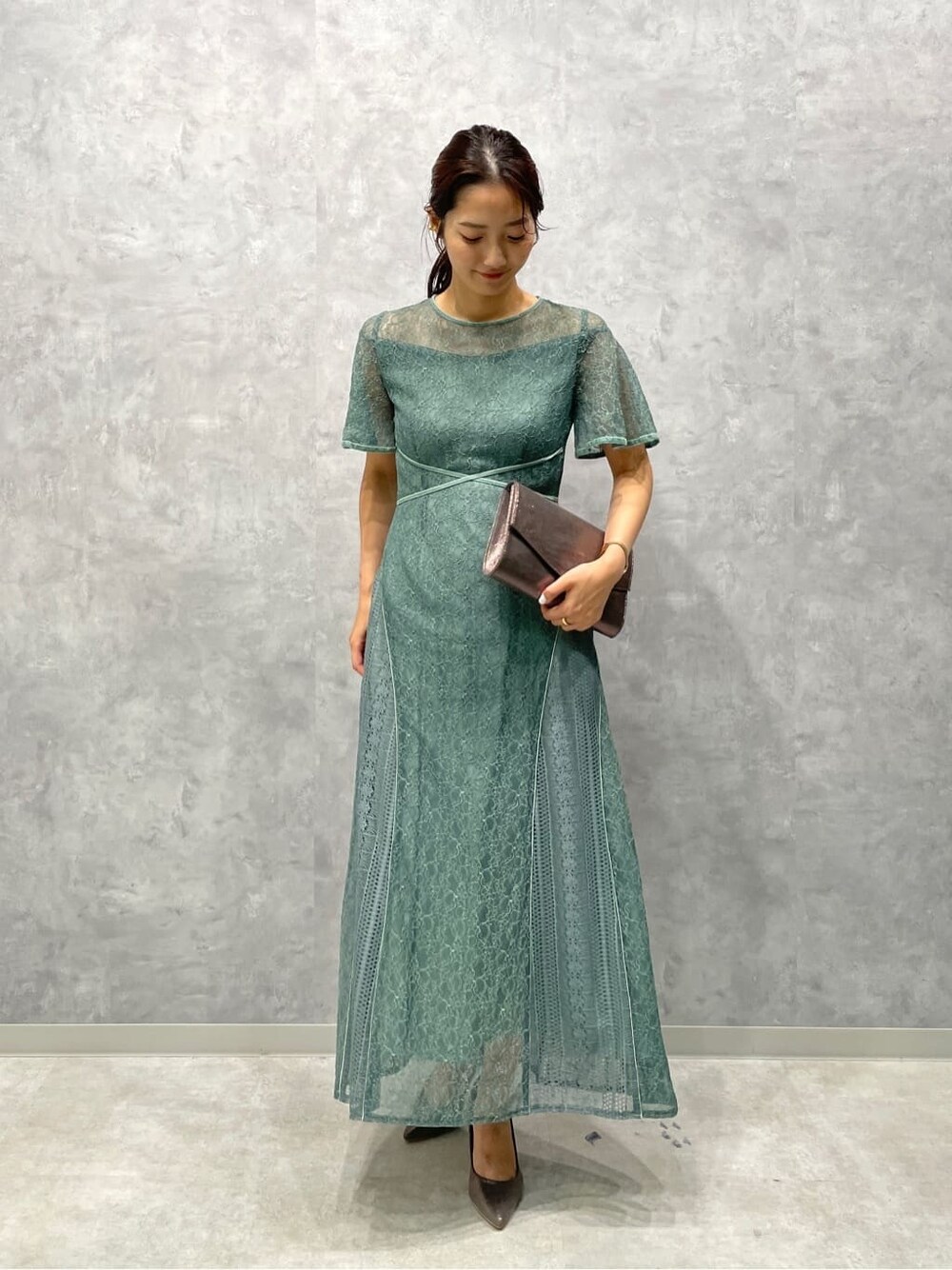 シルバー系のパンプス、シルバー系のクラッチバッグ、グリーン系のドレスを着用したレディースの夏コーディネートの2枚目の写真