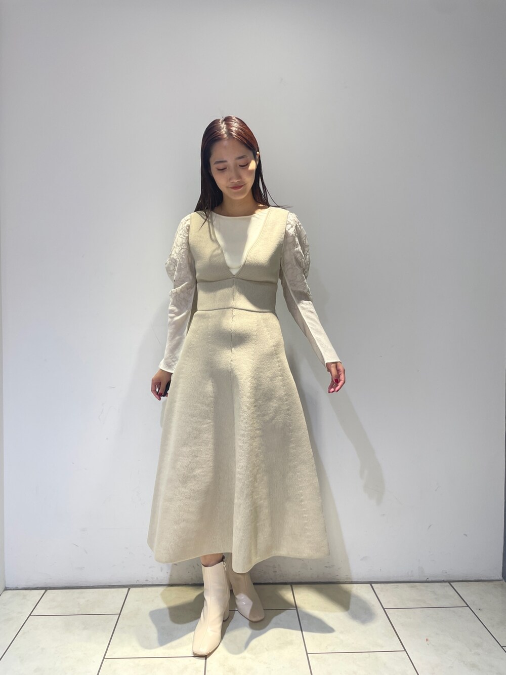 ホワイト系のニット/セーター、ホワイト系のジャンパースカート、ホワイト系のブーツを着用したレディースの秋コーディネートの2枚目の写真