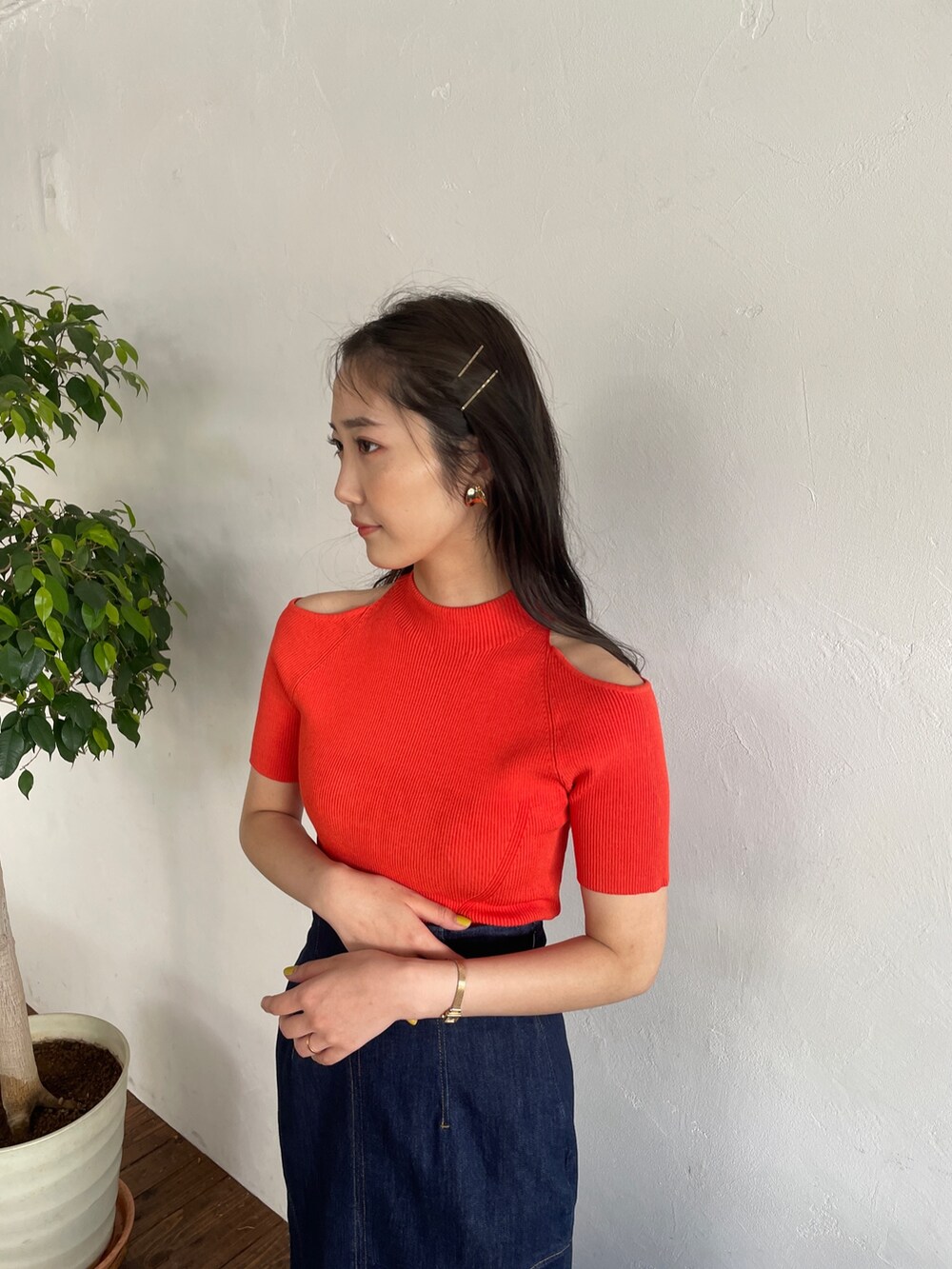 オレンジ系のニット/セーター、ブルー系のデニムスカート、ブラック系のパンプスを着用したレディースの春コーディネートの5枚目の写真