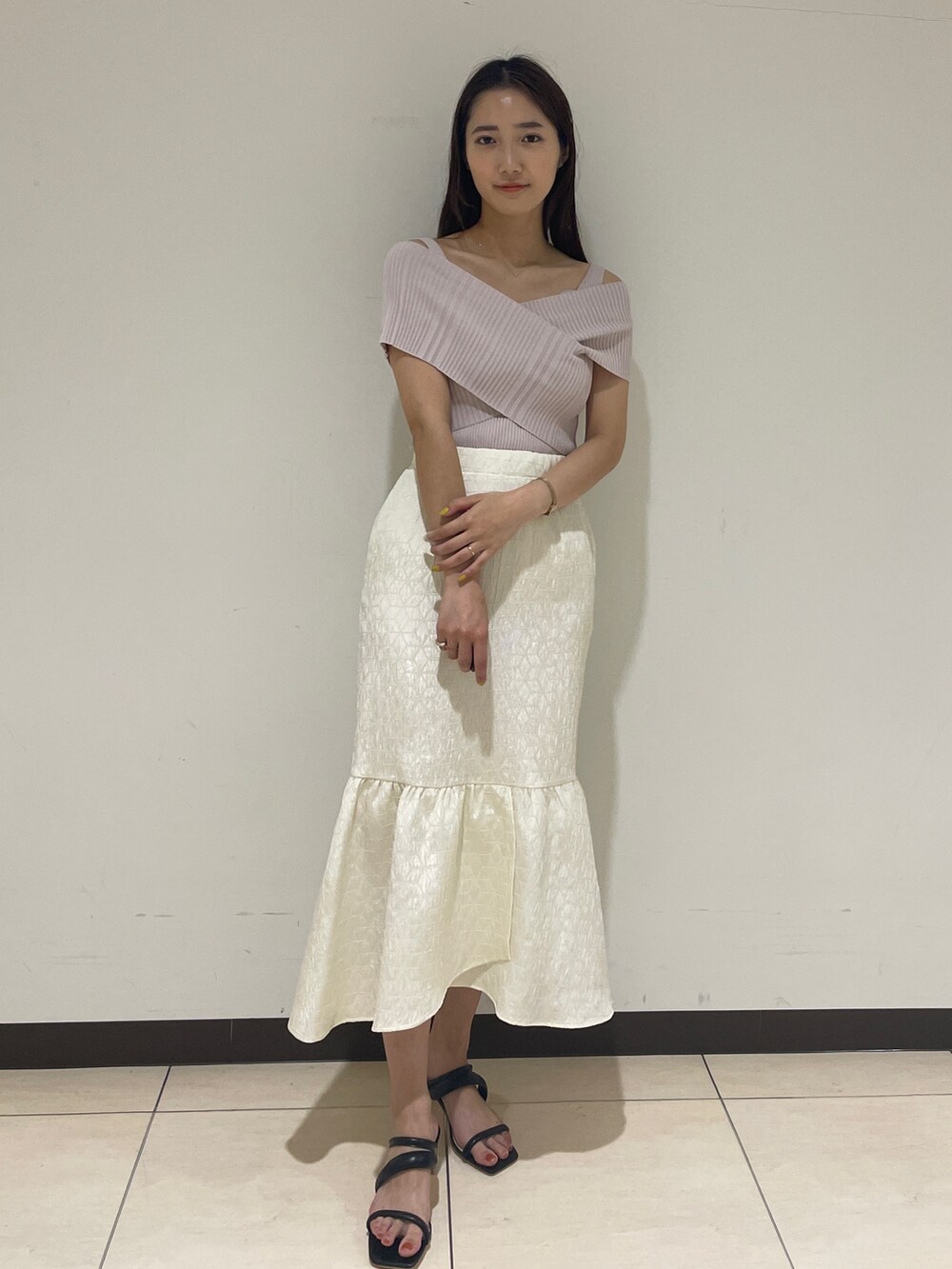 ホワイト系のスカート、ベージュ系のニット/セーター、ブラック系のサンダルを着用したレディースの春コーディネートの3枚目の写真