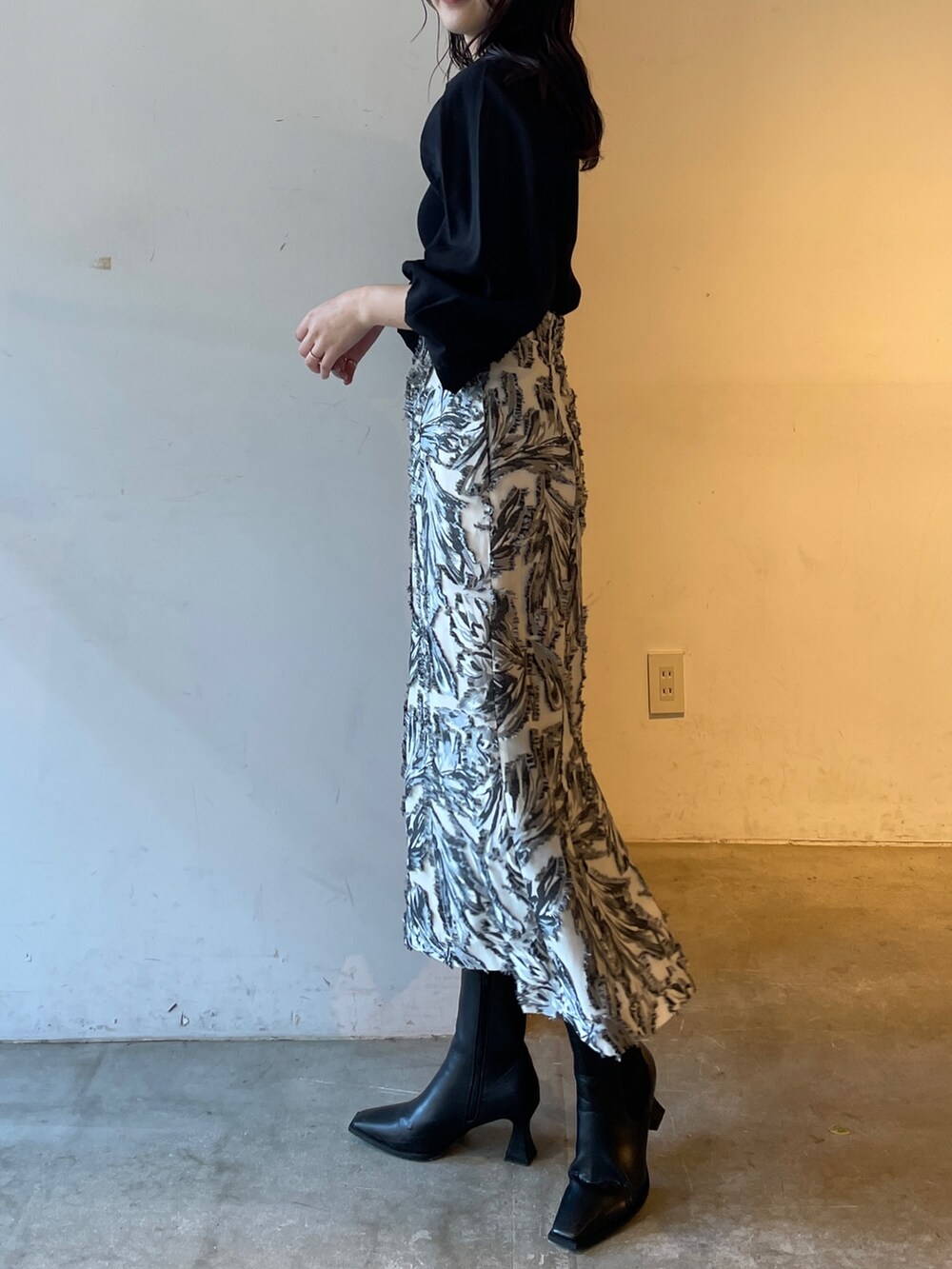 ブラック系のスカート、ブラック系のニット/セーター、ブラック系のブーツを着用したレディースの冬コーディネートの3枚目の写真