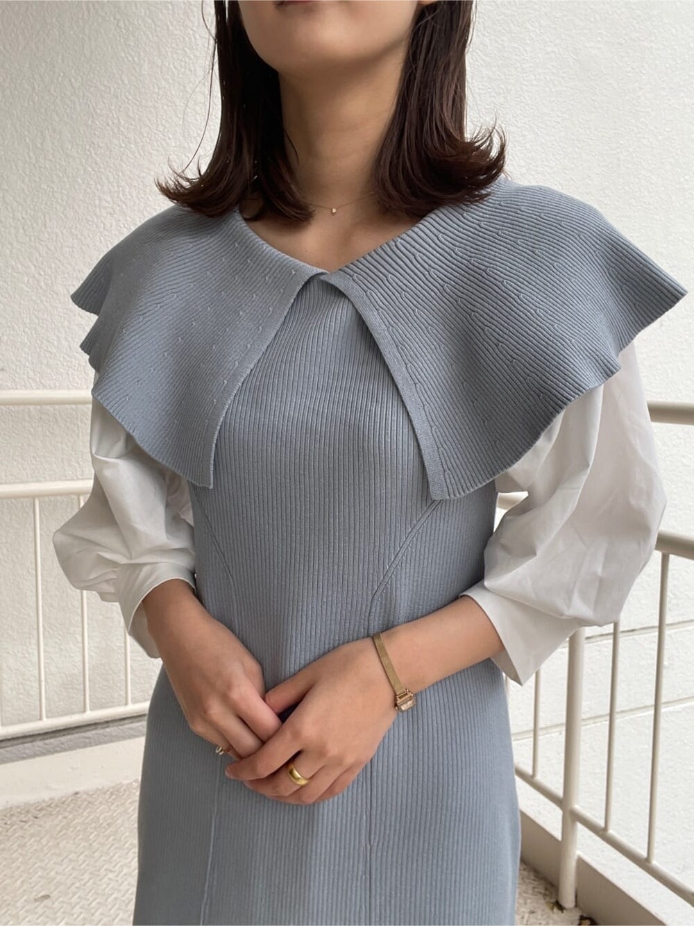 ブルー系のワンピース、ブラック系のハンドバッグ、ホワイト系のパンプスを着用したレディースの冬コーディネートの2枚目の写真