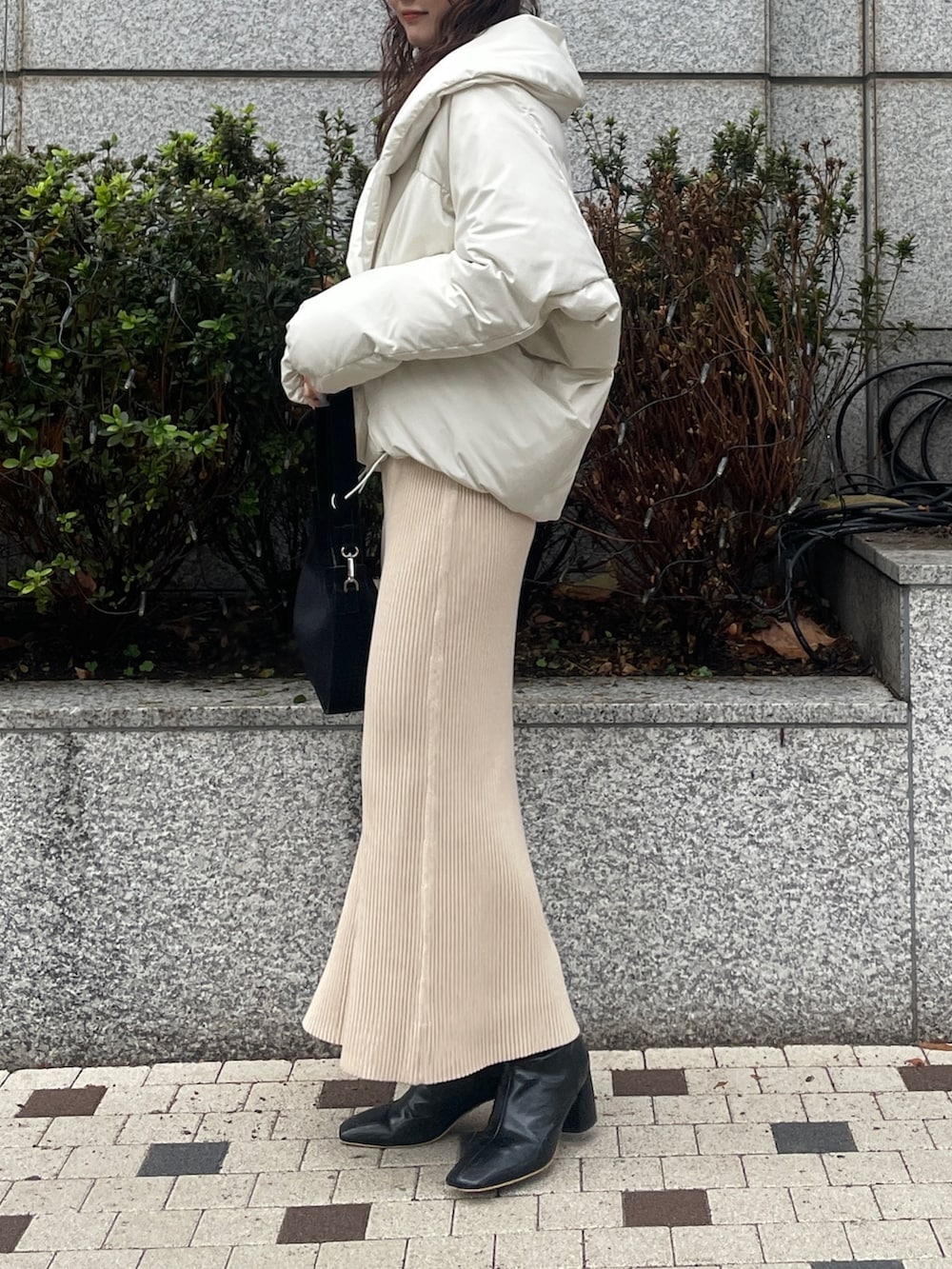 ホワイト系のダウンジャケット/コート、ベージュ系のワンピース、ブラック系のブーツを着用したレディースの冬コーディネートの4枚目の写真