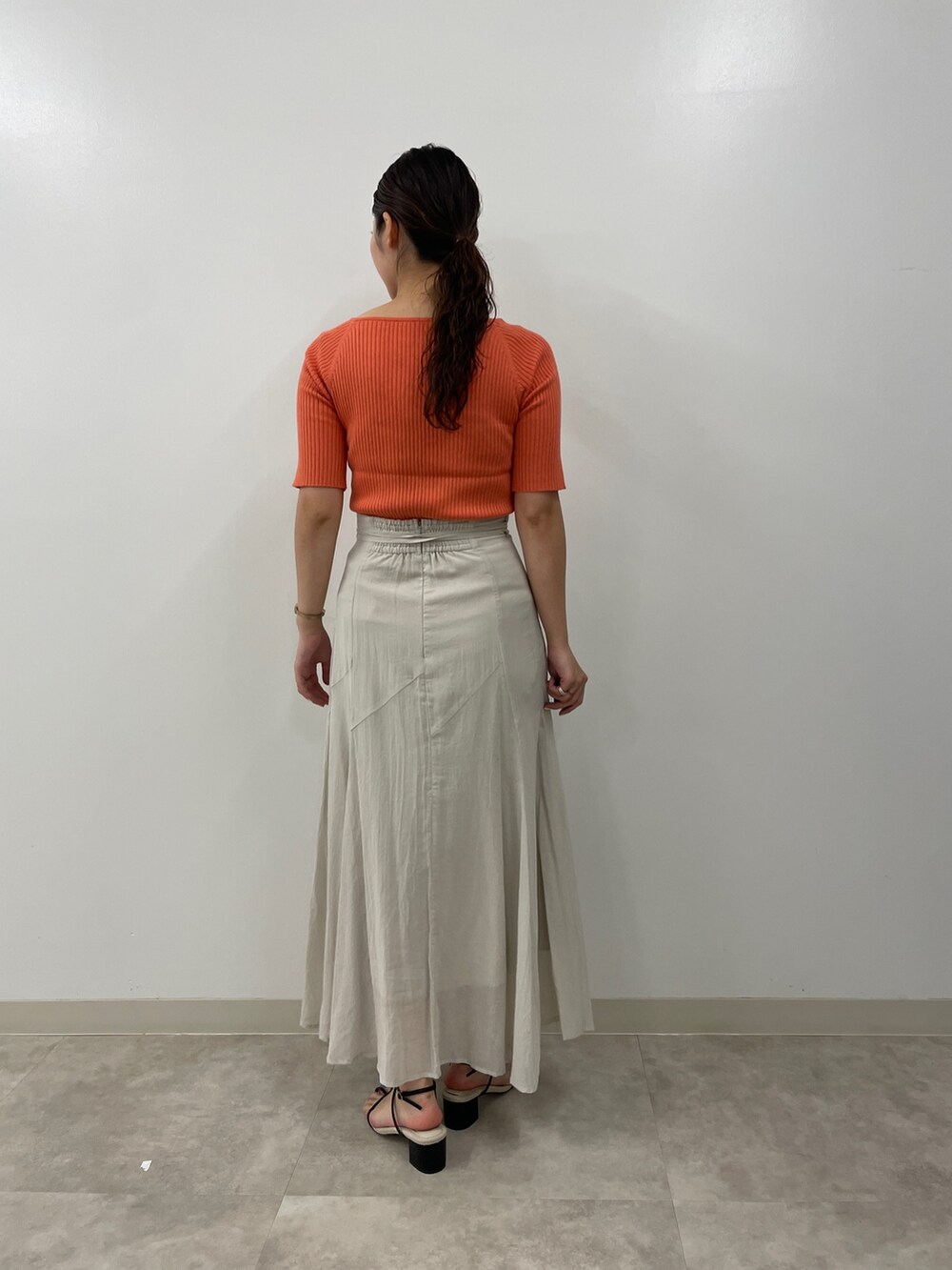 グレー系のスカート、ピンク系のニット/セーター、ブラック系のサンダルを着用したレディースの夏コーディネートの5枚目の写真