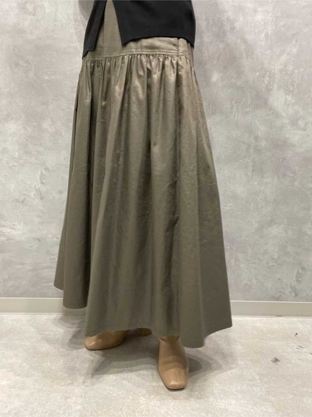 ベージュ系のスカート、ベージュ系のブーツ、ブラック系のニット/セーターを着用したレディースの秋コーディネートの7枚目の写真