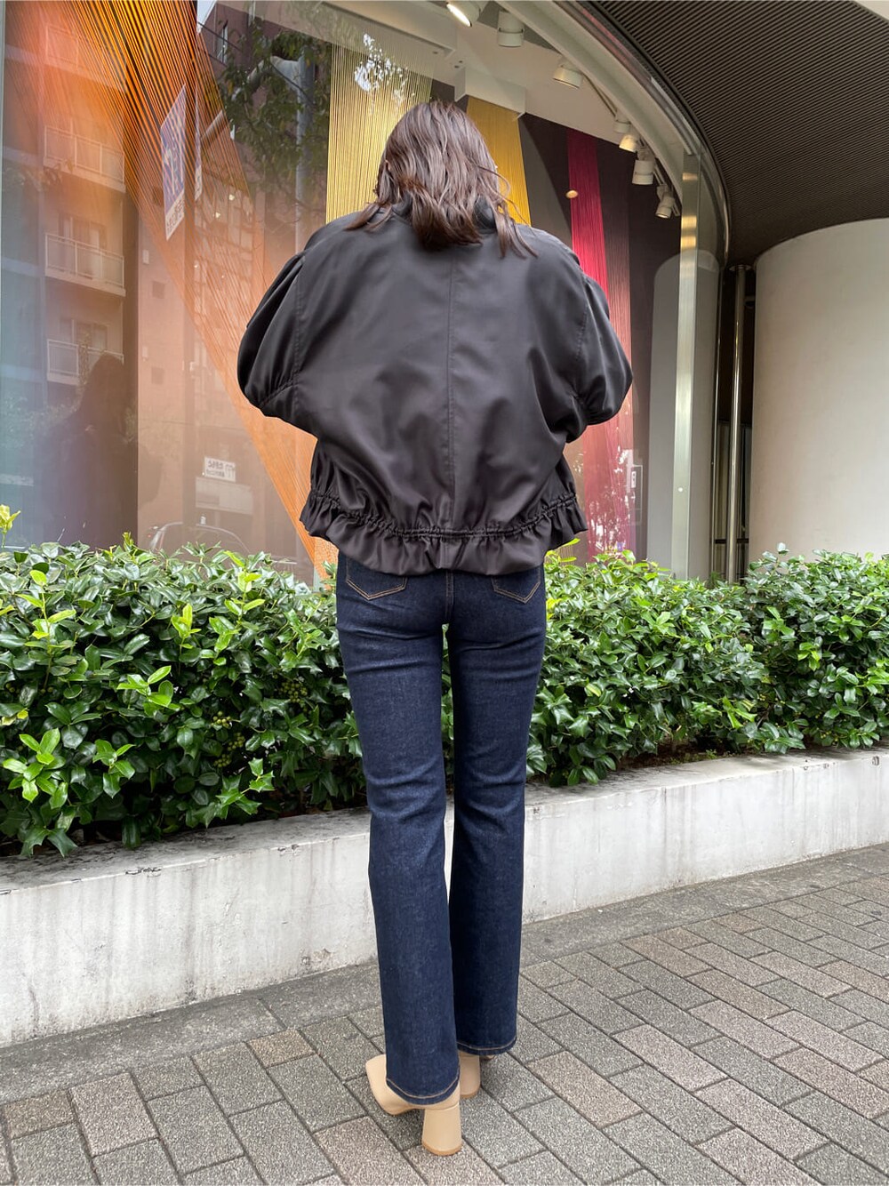 ベージュ系のシャツ/ブラウス、ブラック系のブルゾン、ブルー系のデニムパンツを着用したレディースの秋コーディネートの3枚目の写真