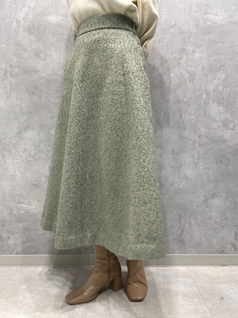 ベージュ系のブーツ、ホワイト系のニット/セーター、グリーン系のスカートを着用したレディースの冬コーディネートの10枚目の写真