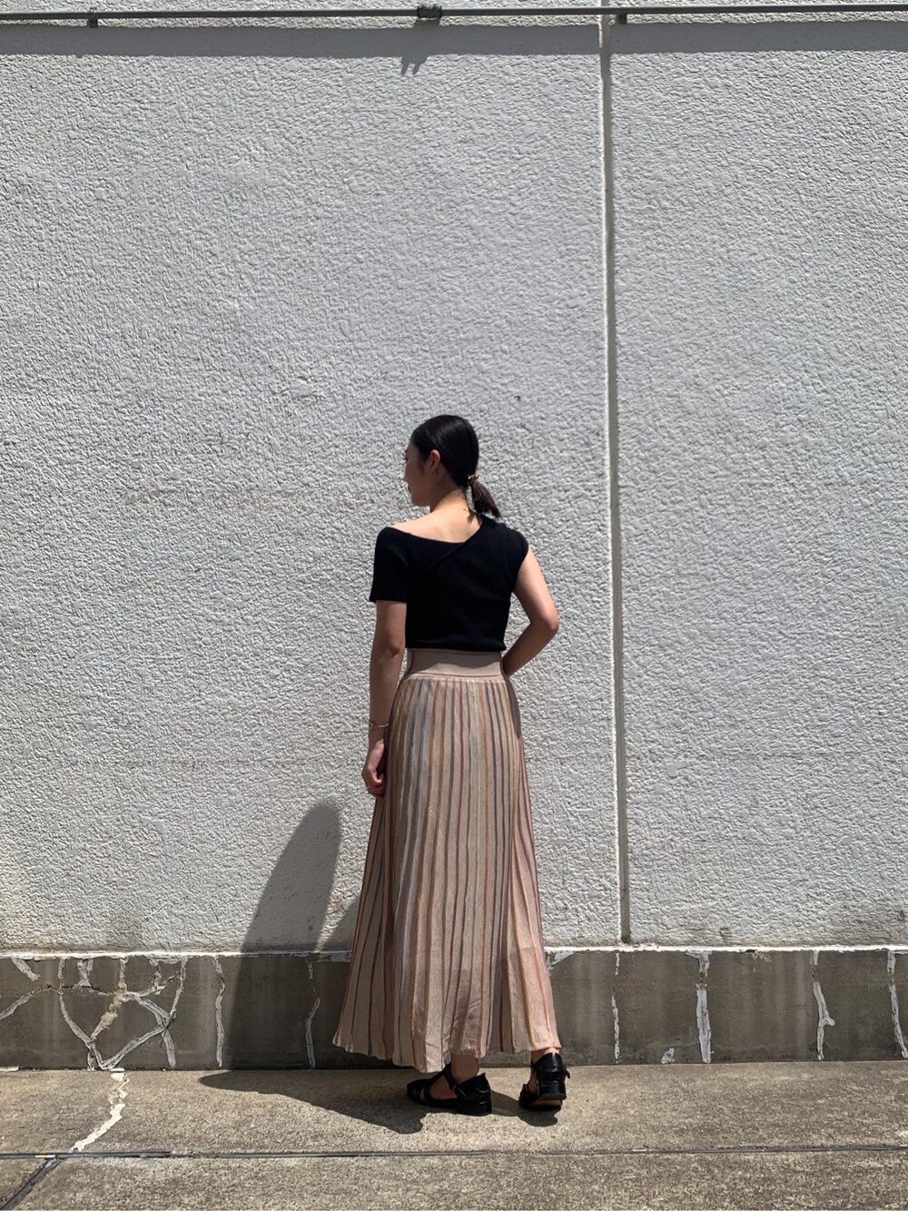 ベージュ系のスカート、ブラック系のニット/セーター、ゴールド系のバングル/リストバンドを着用したレディースの春コーディネートの6枚目の写真