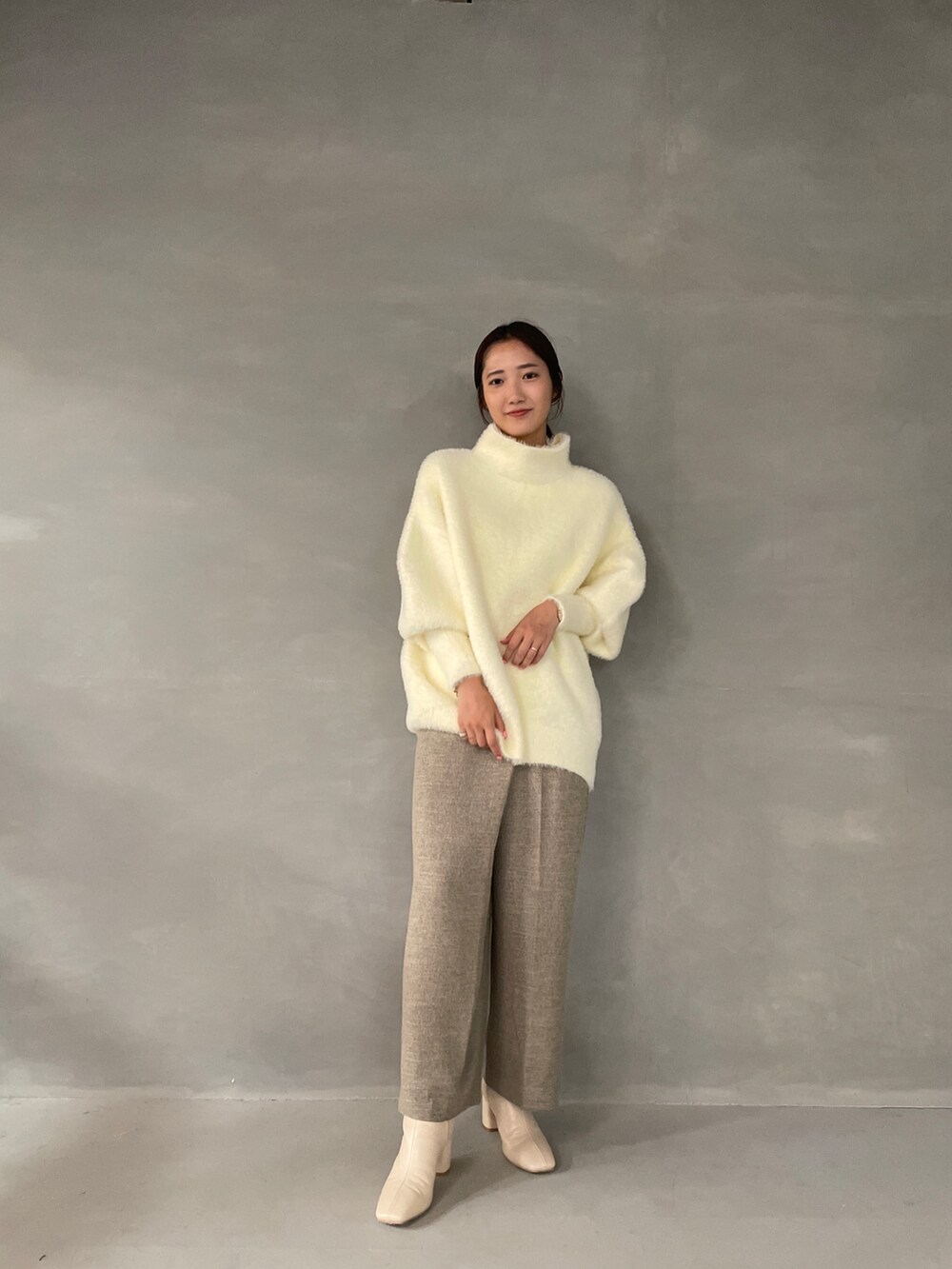 ホワイト系のニット/セーター、ベージュ系のその他パンツ、ホワイト系のブーツを着用したレディースの夏コーディネートの3枚目の写真