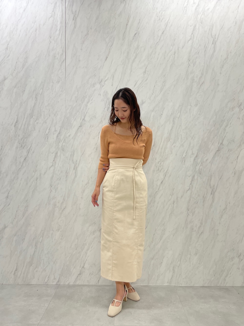 ホワイト系のパンプス、オレンジ系のニット/セーター、ホワイト系のスカートを着用したレディースの冬コーディネートの4枚目の写真