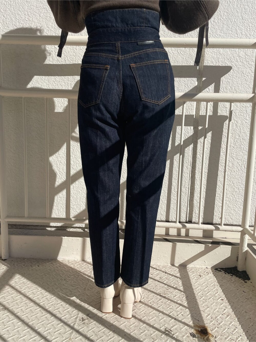 ホワイト系のその他シューズ、ブラウン系のニット/セーター、ブルー系のデニムパンツを着用したレディースの冬コーディネートの7枚目の写真