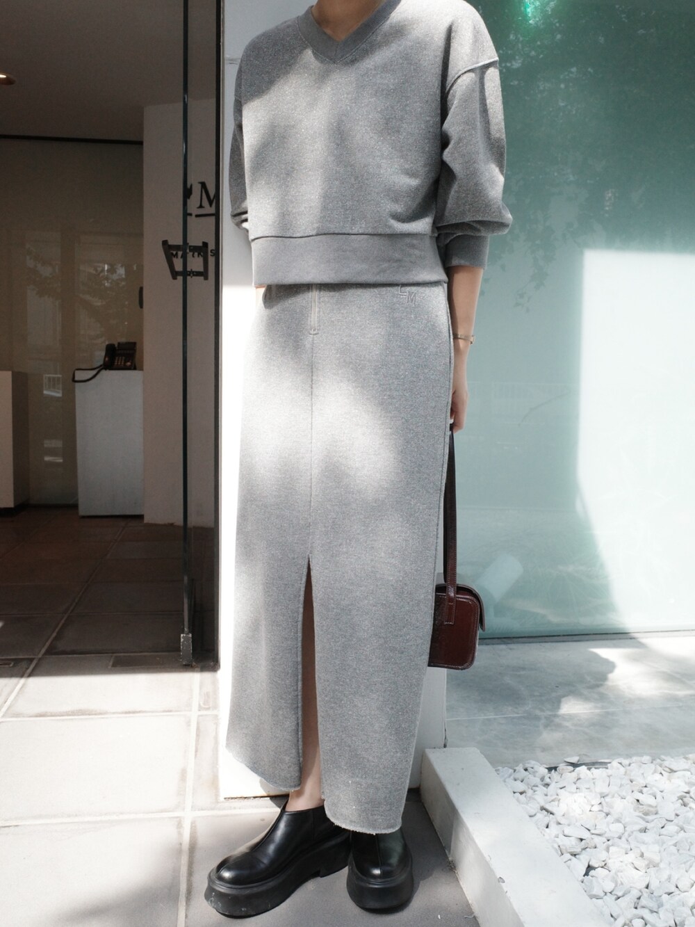 グレー系のスカート、グレー系のスウェット、ブラック系のブーツを着用したレディースの夏コーディネートの7枚目の写真