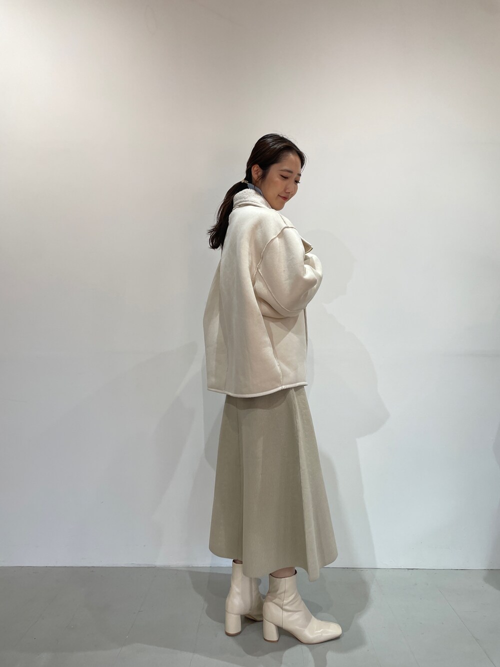 ブルー系のニット/セーター、ホワイト系のジャンパースカート、ホワイト系のブーツを着用したレディースの夏コーディネートの4枚目の写真